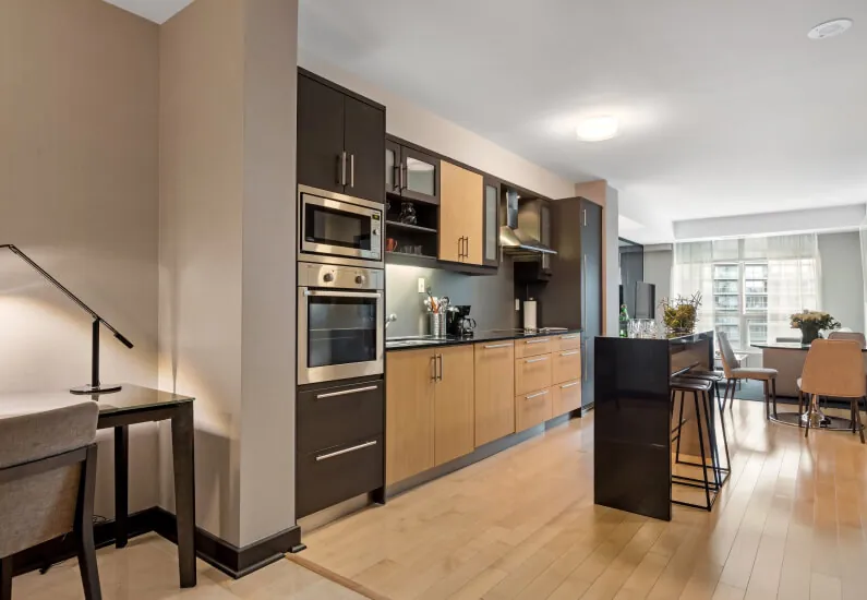 Contemporary kitchen renovation with two-tone custom Ann Tucker cabinets, wood grain and dark finishes, stainless steel appliances, and open concept layout by Design First Builders in Chicago