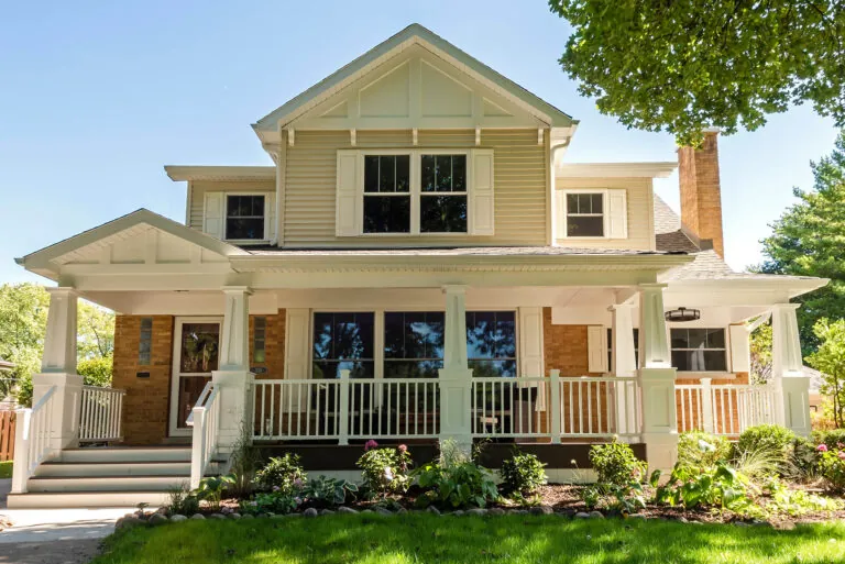 Beautifully renovated two-story home with a spacious front porch, white railings, and craftsman-style architectural details