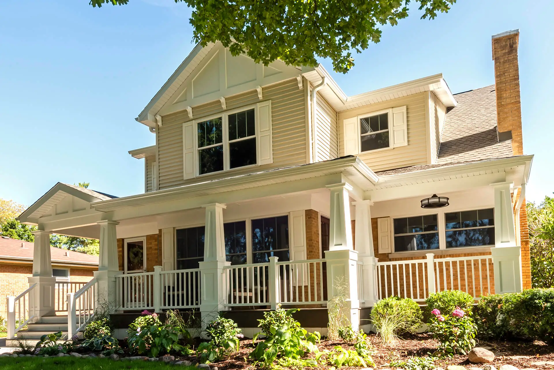 Beautifully renovated two-story home with a spacious front porch, white railings, and craftsman-style architectural details