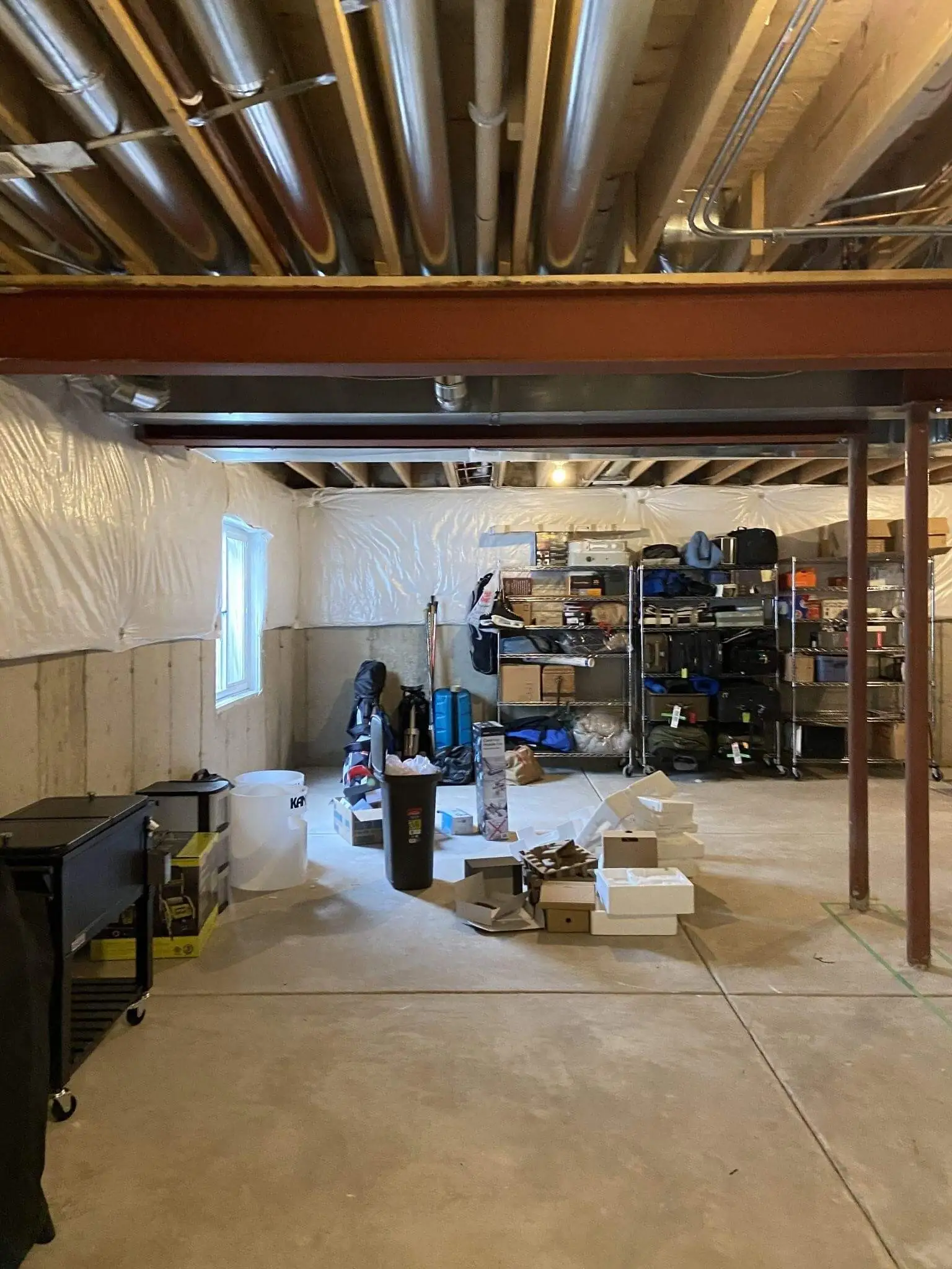 Unfinished basement renovation showing exposed ceiling joists, HVAC ductwork, and construction materials before remodeling by Design First Builders in Itasca, IL