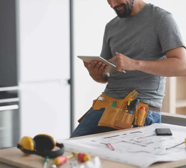 Construction Project Management with BuilderTrend | Design First Builders Construction project manager using BuilderTrend digital tools and tablet for project coordination with blueprints and construction plans at Design First Builders in Chicago