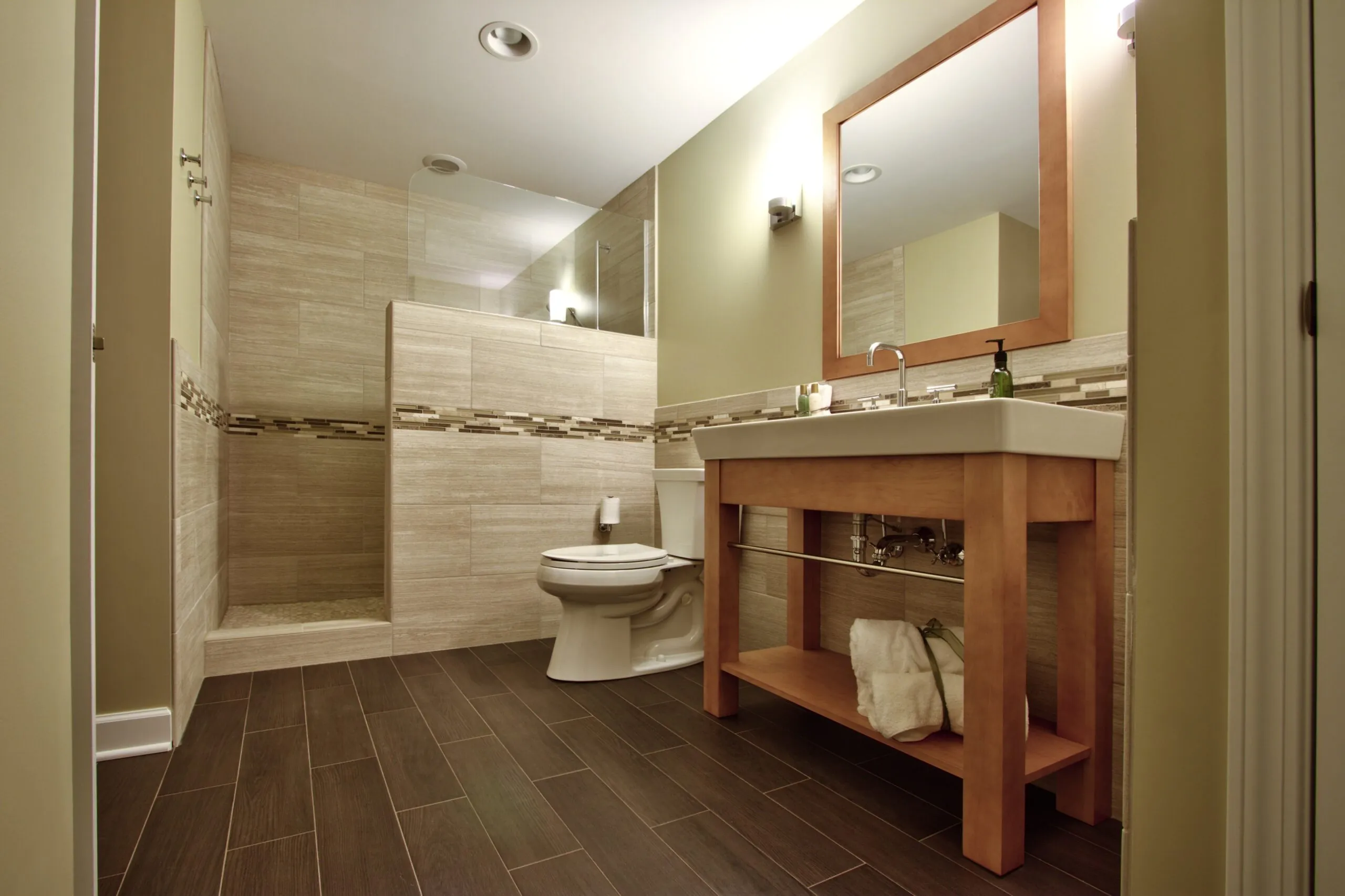 Basement bathroom renovation by Design First Builders featuring wood-look tile walls, custom wood vanity, mosaic accent border, walk-in shower, and modern fixtures in Illinois