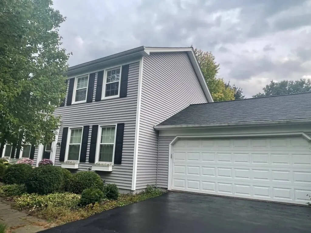 Before photo of gray vinyl siding house with black shutters and white garage door prior to Design First Builders renovation in Illinois