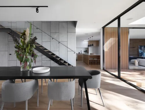 Modern home renovation by Design First Builders featuring floating staircase with cable railings, open concept dining and kitchen, wood slat accent wall, and contemporary design in Illinois