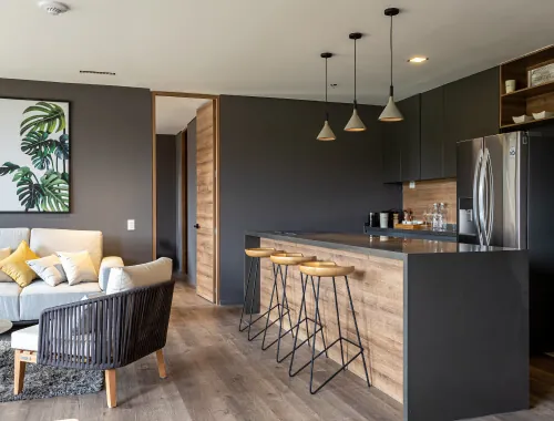 Modern kitchen renovation by Design First Builders featuring dark cabinets, wood waterfall island, black pendant lights, stainless steel appliances, and open concept design in Illinois