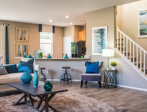 Open concept home renovation by Design First Builders featuring kitchen island, living room seating, blue accent decor, staircase, and modern design in Illinois