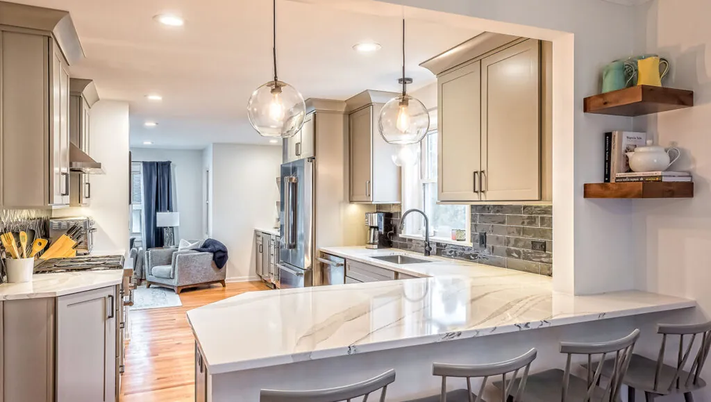 Design First Builders Park Ridge open concept kitchen with large quartz island, bar seating, floating wood shelves, and view to living room