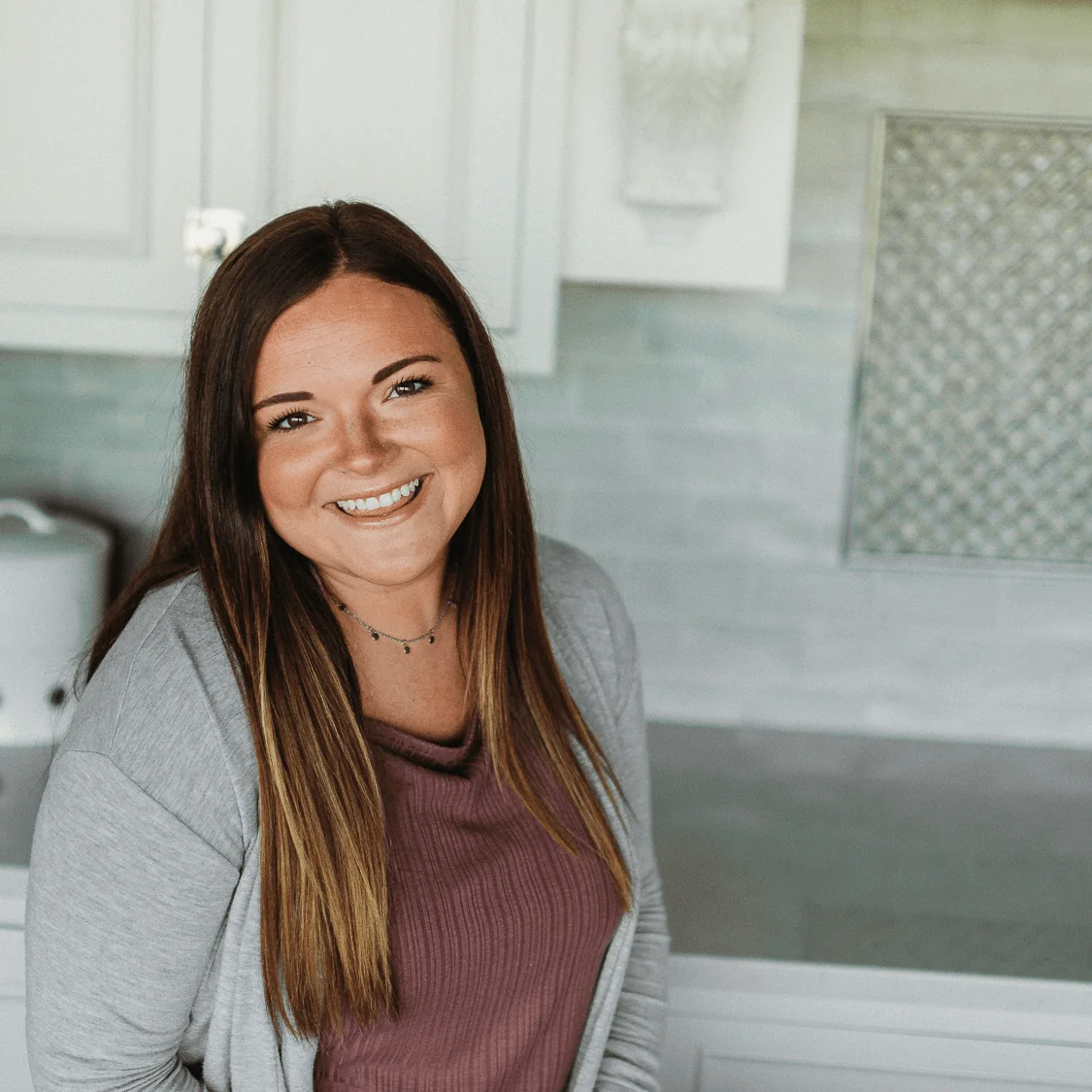Alyssa Korinek, Human Resource & Marketing Manager at Design First Builders, professional headshot in white kitchen setting in Chicago