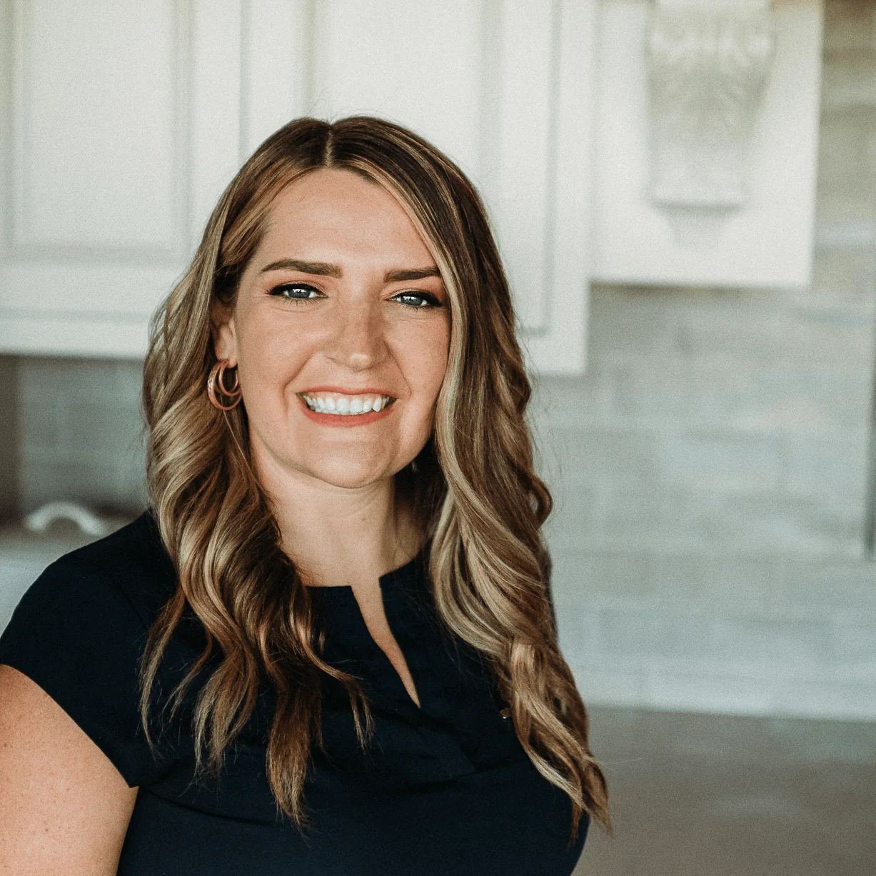 Heather Hudson, Director of Architectural Design at Design First Builders, professional headshot in white kitchen setting in Chicago