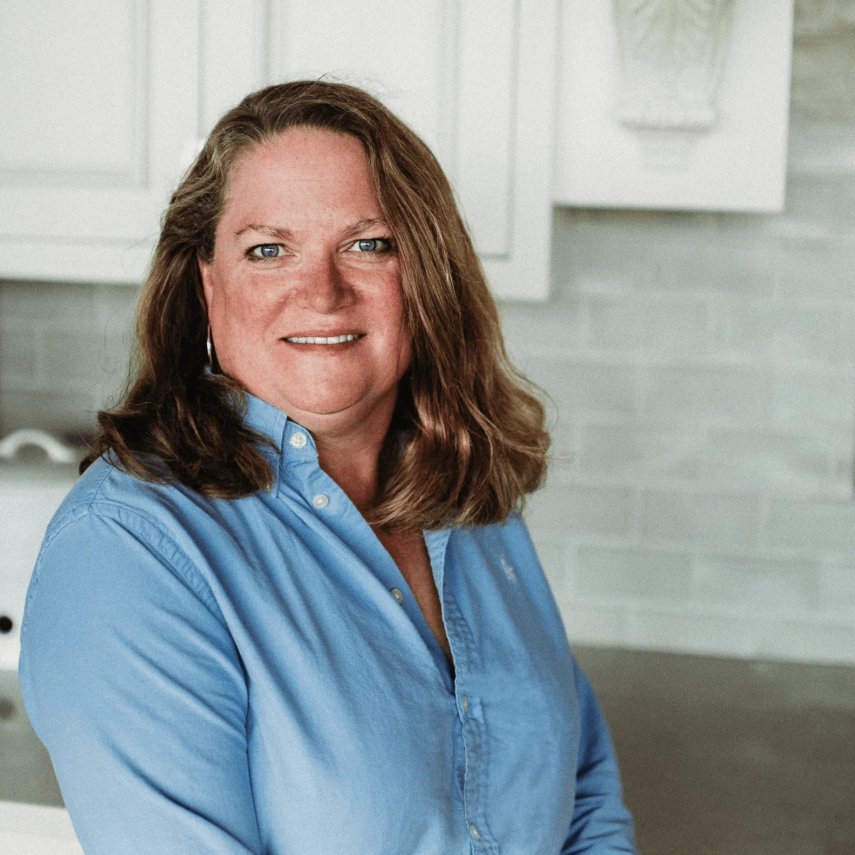 Jennifer Kruse, Design Architect at Design First Builders, professional headshot in white kitchen setting in Chicago