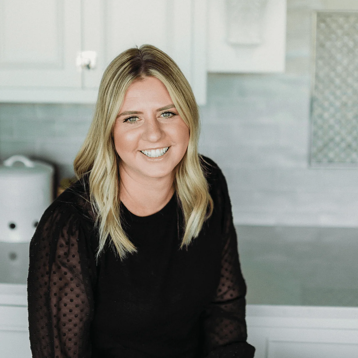Krista Hansen, Marketing Specialist at Design First Builders, professional headshot in white kitchen setting in Chicago