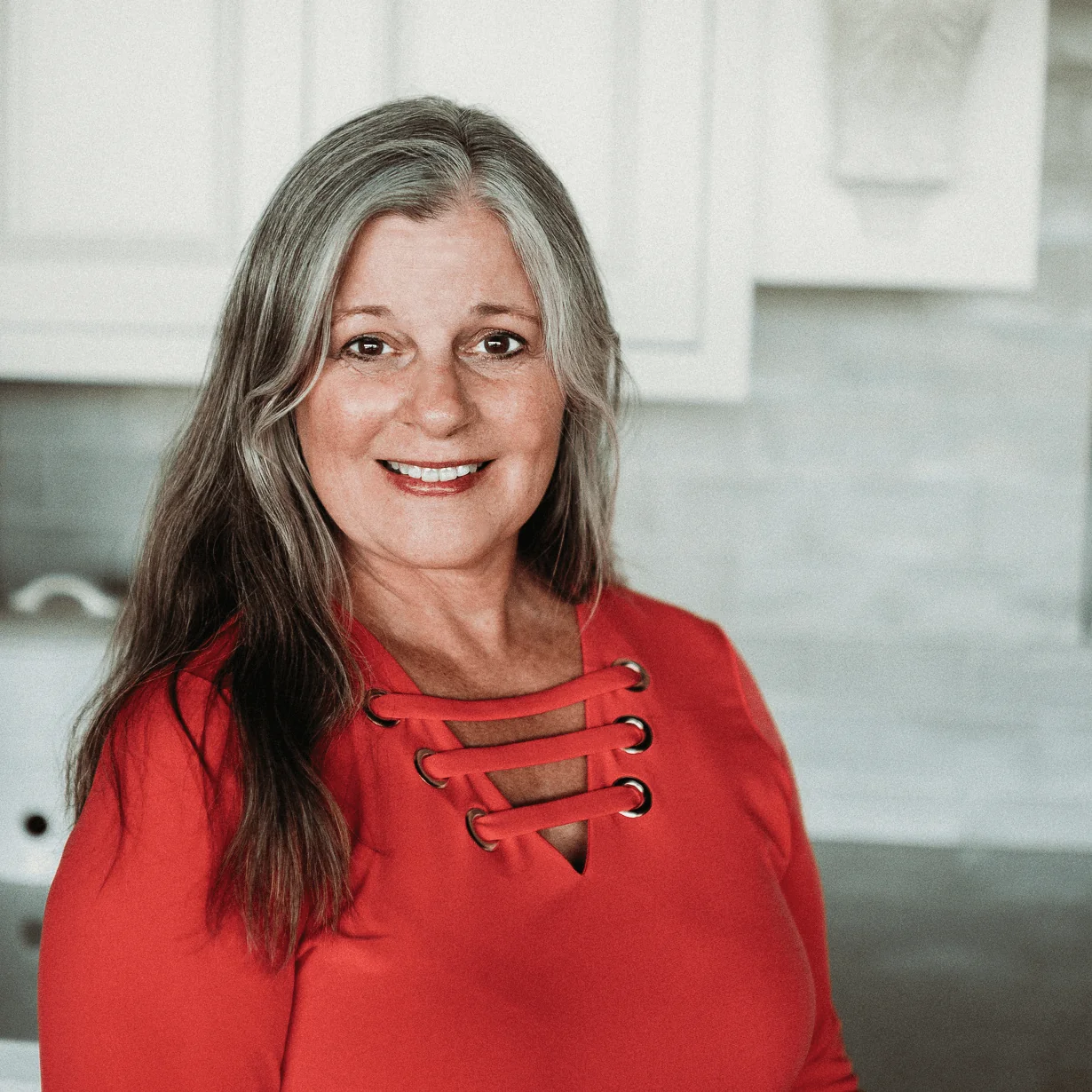 Linda Larisch CMKBD, Senior Architectural Designer at Design First Builders, professional headshot in white kitchen setting in Chicago