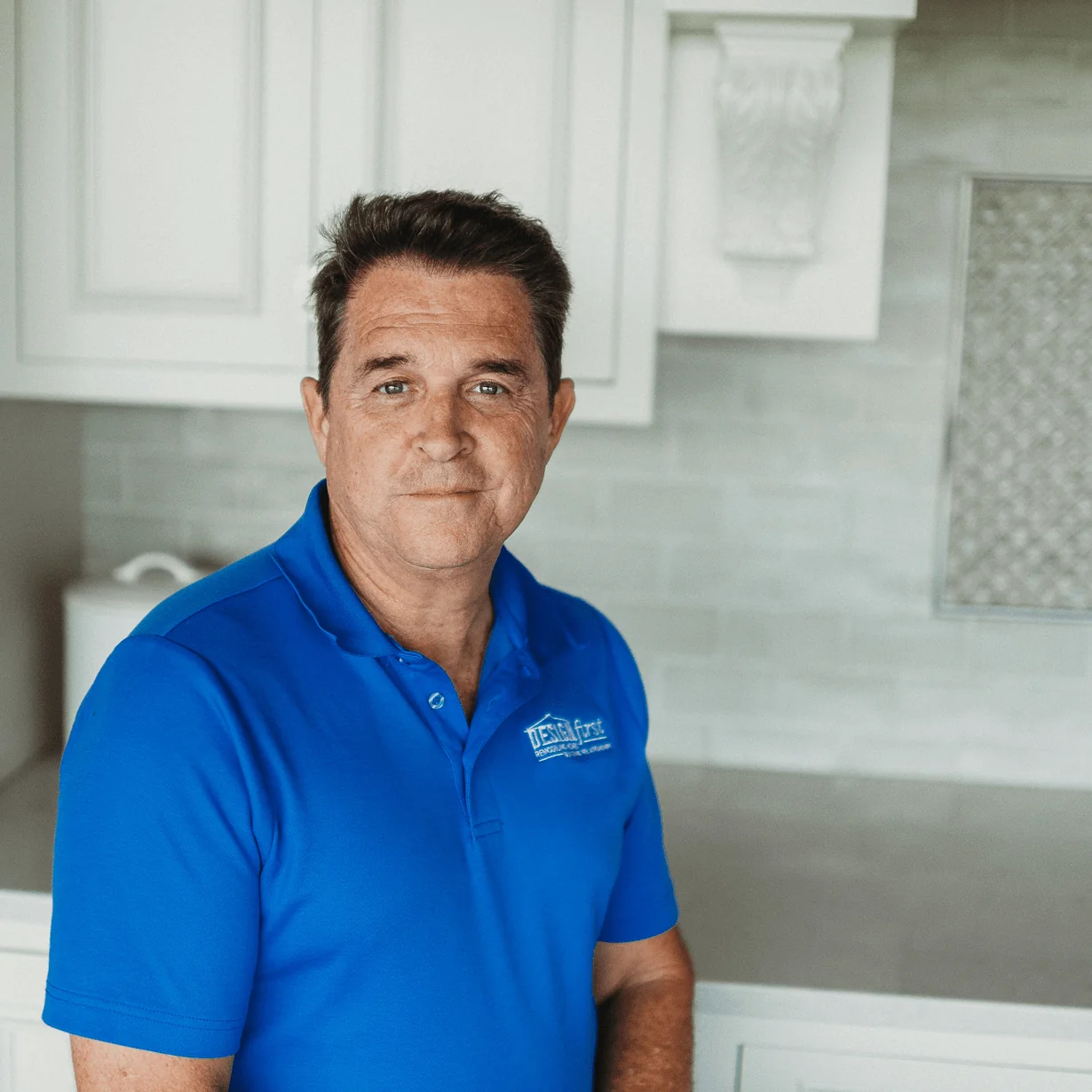 Rick Divito, Project Manager at Design First Builders, professional headshot wearing company polo in white kitchen setting in Chicago