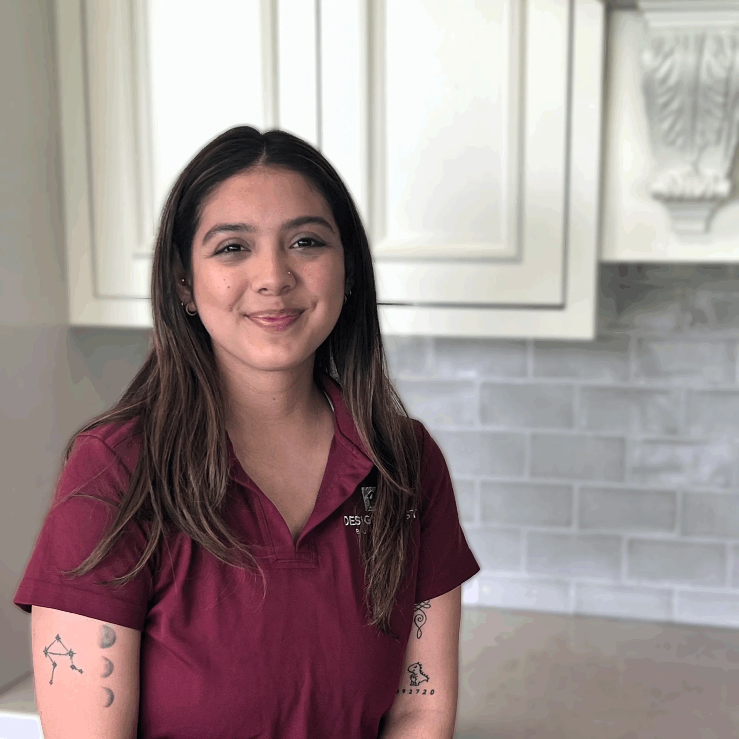 Stephanie Hernandez, Construction Admin at Design First Builders, professional headshot wearing company polo in white kitchen setting in Chicago