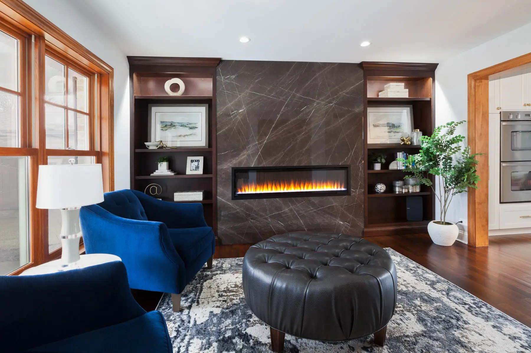 Contemporary living room renovation with dramatic marble fireplace wall, custom built-in shelving, linear fireplace, and open concept design by Design First Builders in Chicago